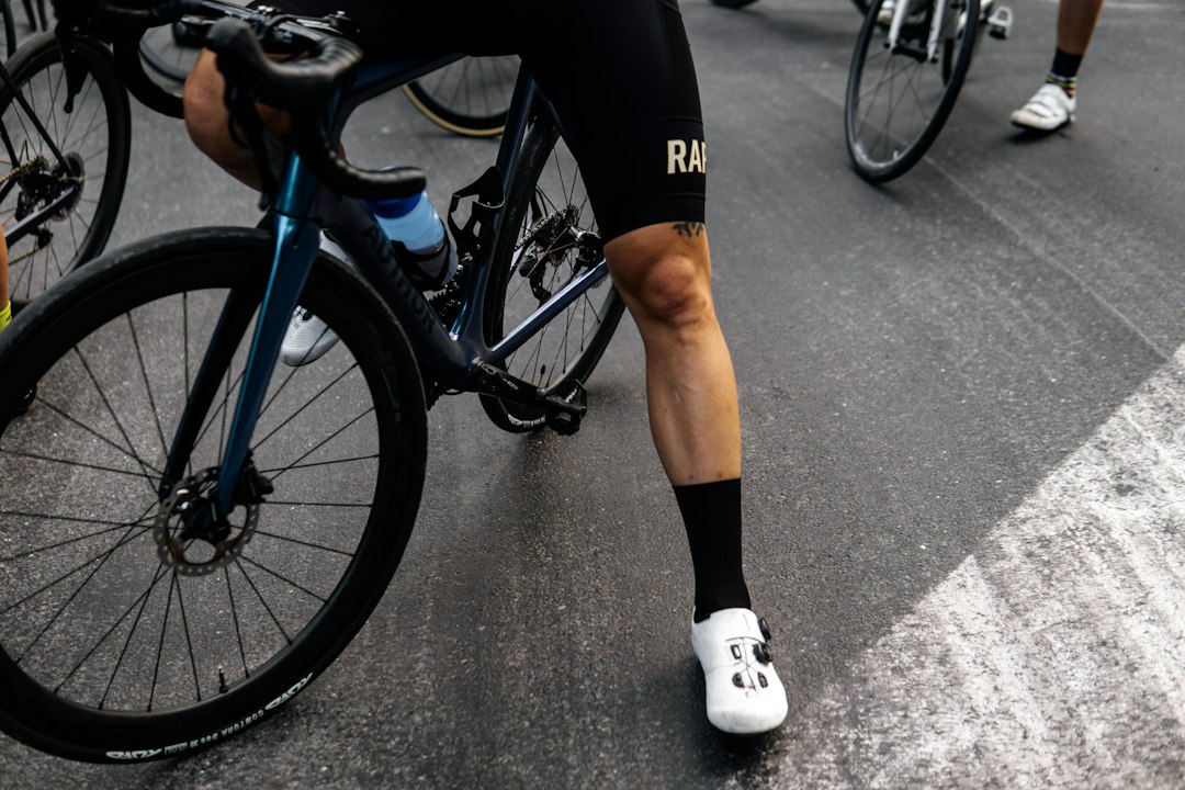 Close-up of a cyclist pedaling on a road bike with a power meter visible.