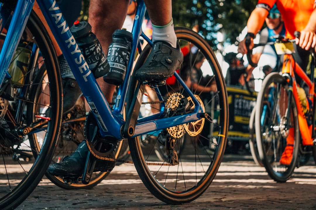 Close-up of a cyclist pedaling on a road bike with a power meter visible.