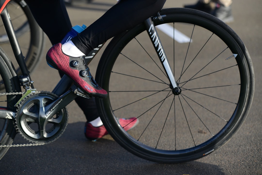 Close-up of a cyclist pedaling on a road bike with a power meter visible.