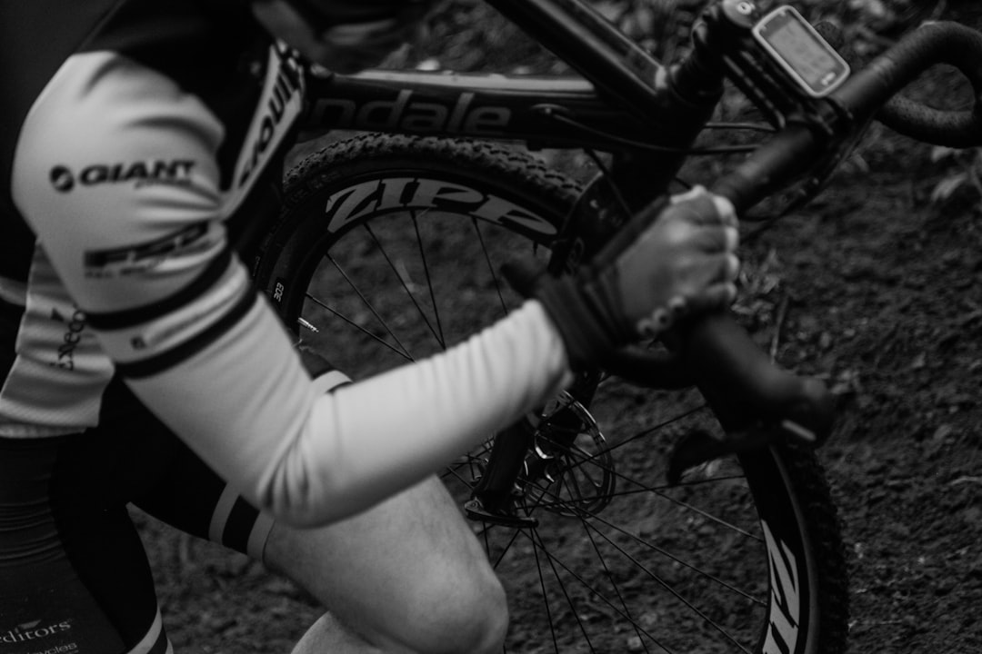 Close-up of a cyclist pedaling on a road bike with a power meter visible.