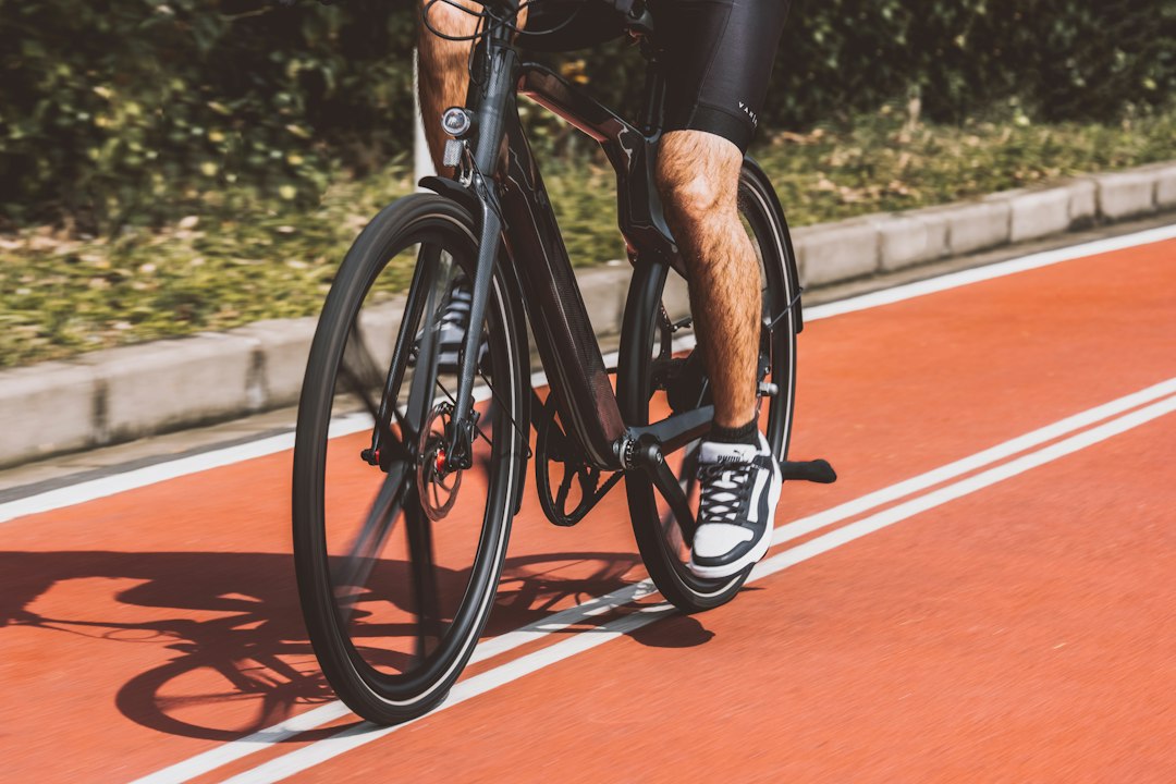 Close-up of a cyclist pedaling on a road bike with a power meter visible.