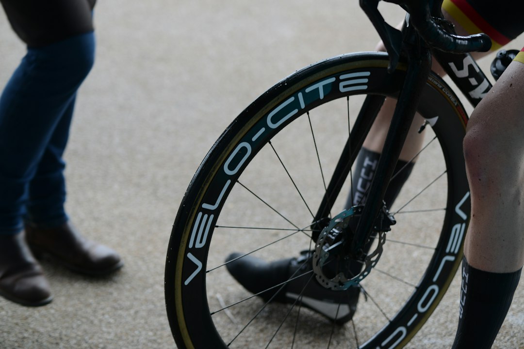 Close-up of a cyclist pedaling on a road bike with a power meter visible.