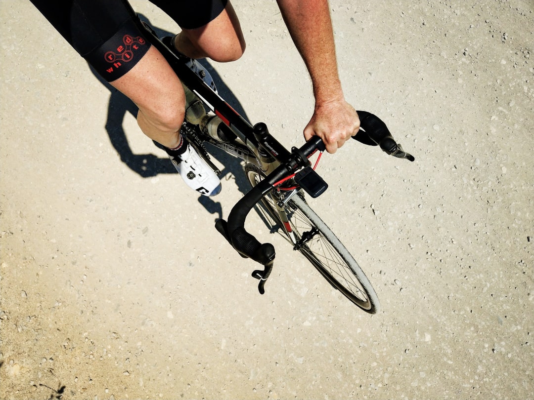 Close-up of a cyclist pedaling on a road bike with a power meter visible.