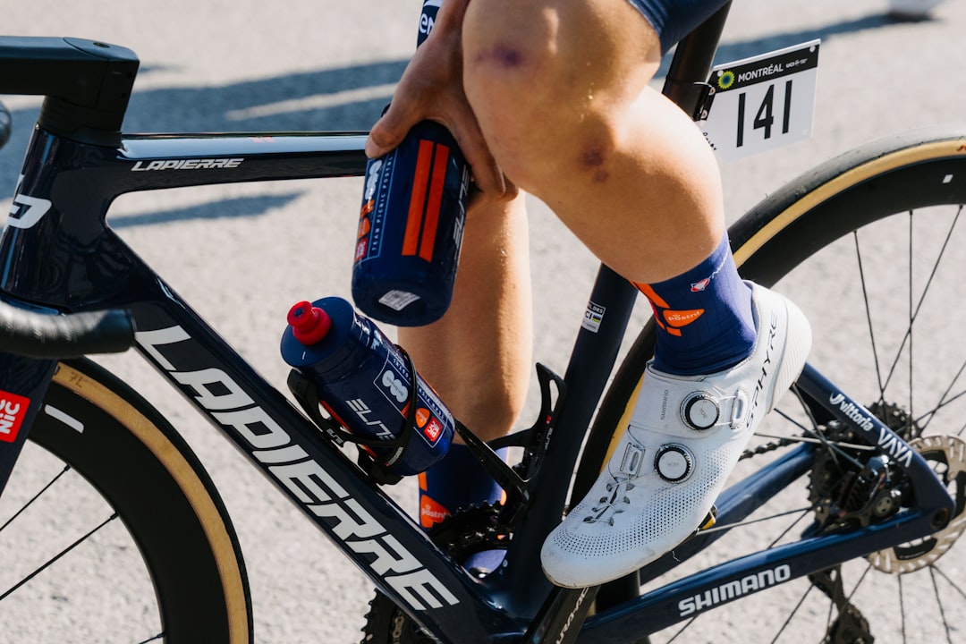 Close-up of a cyclist pedaling on a road bike with a power meter visible.