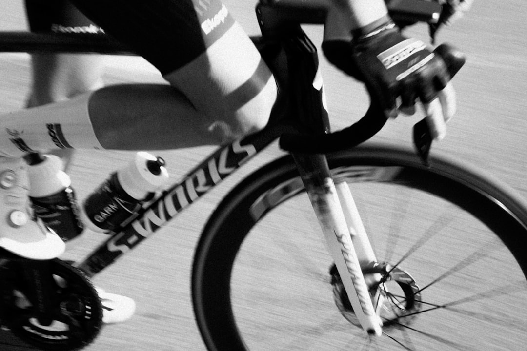 Close-up of a cyclist pedaling on a road bike with a power meter visible.