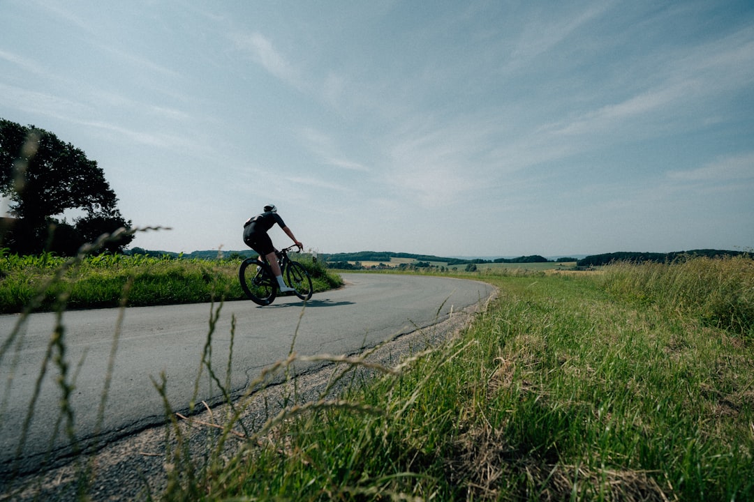 Close-up of a cyclist pedaling on a road bike with a power meter visible.