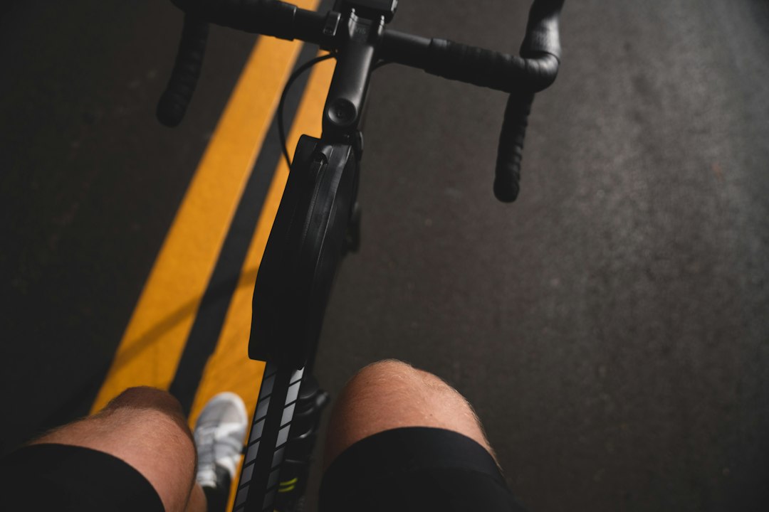 Close-up of a cyclist pedaling on a road bike with a power meter visible.