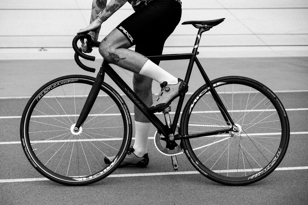 Close-up of a cyclist pedaling on a road bike with a power meter visible.