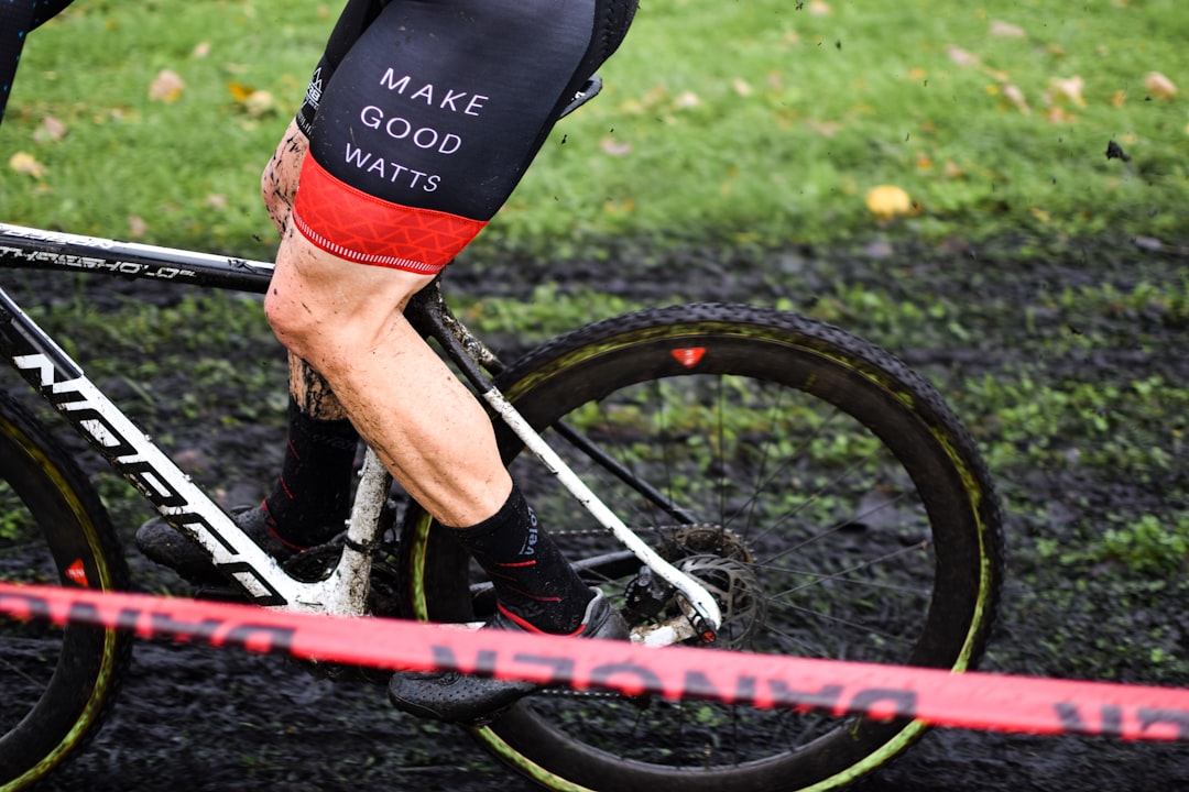 Close-up of a cyclist pedaling on a road bike with a power meter visible.