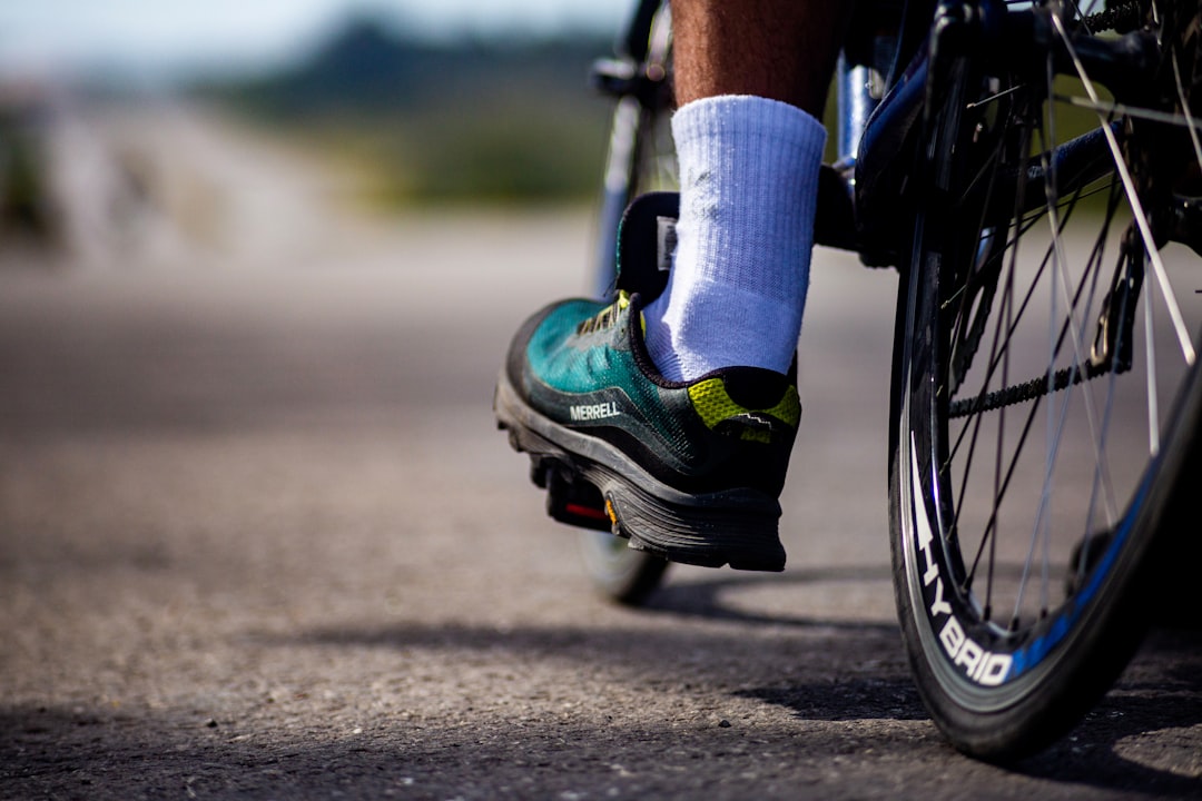 Close-up of a cyclist pedaling on a road bike with a power meter visible.