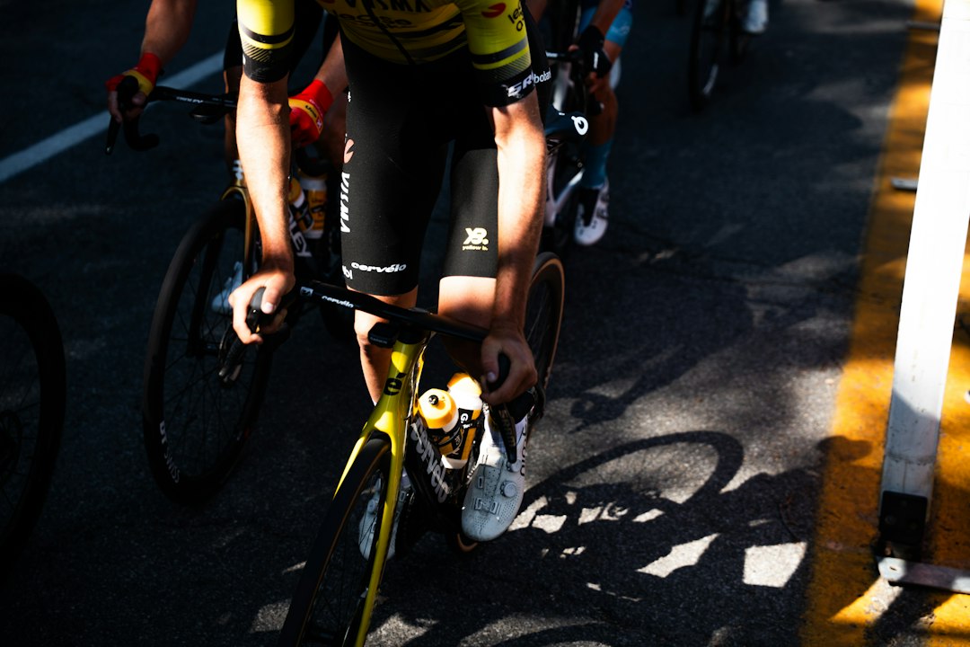 Close-up of a cyclist pedaling on a road bike with a power meter visible.