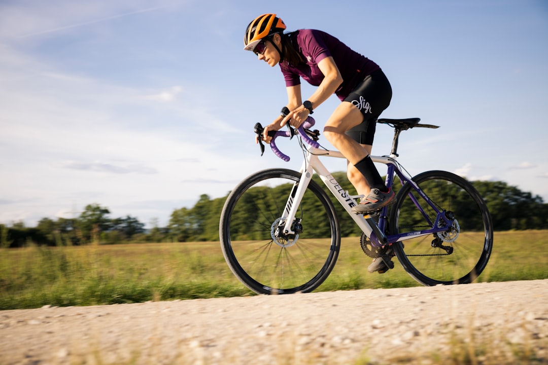 Close-up of a cyclist pedaling on a road bike with a power meter visible.