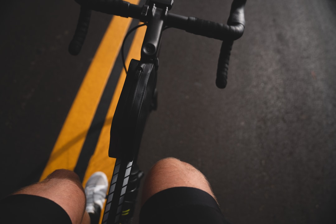 Close-up of a cyclist pedaling on a road bike with a power meter visible.