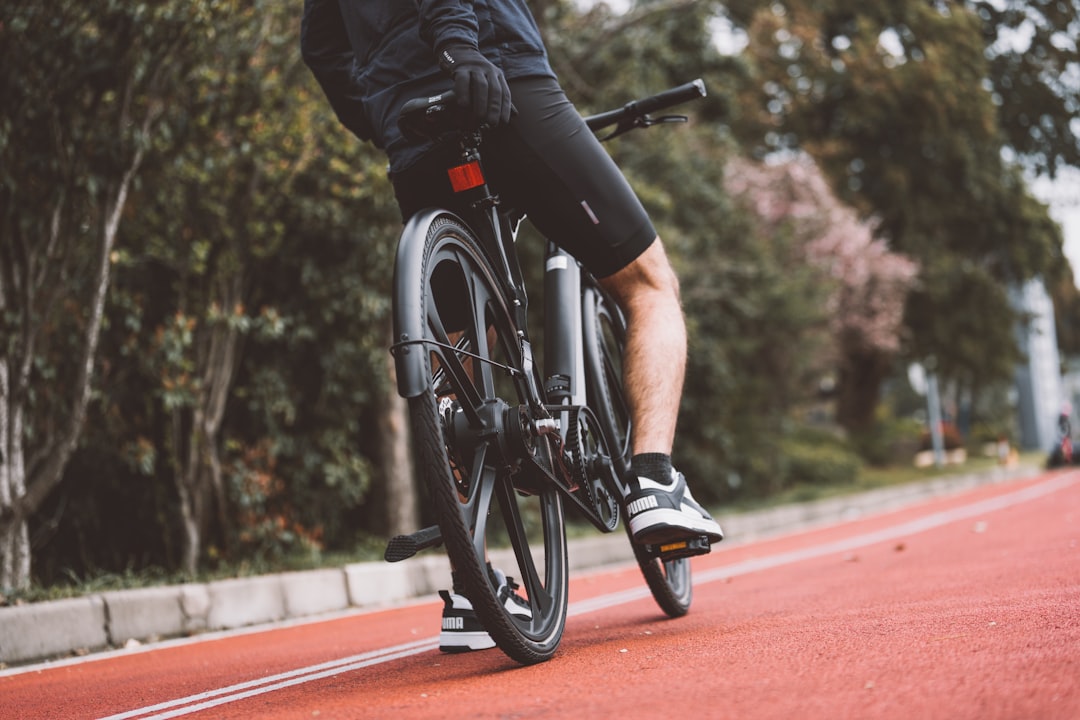 Close-up of a cyclist pedaling on a road bike with a power meter visible.