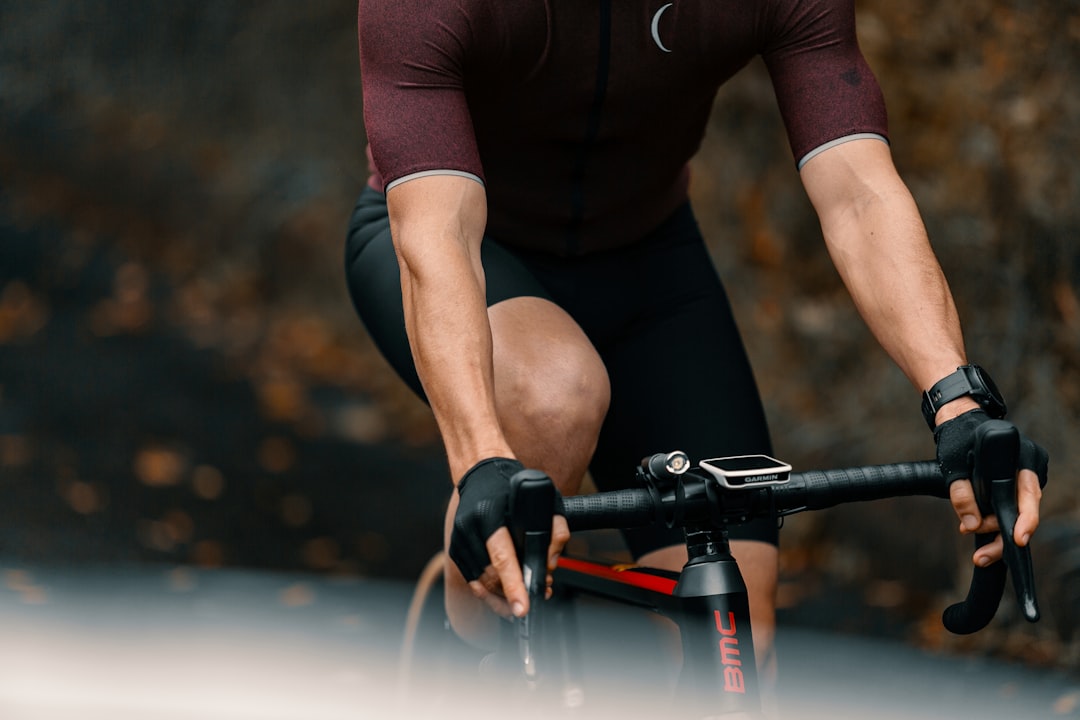 Close-up of a cyclist pedaling on a road bike with a power meter visible.