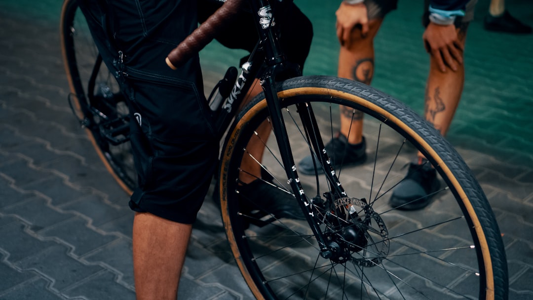 Close-up of a cyclist pedaling on a road bike with a power meter visible.