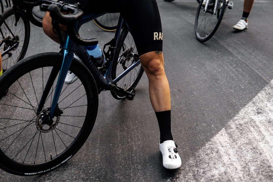 Close-up of a cyclist pedaling on a road bike with a power meter visible.