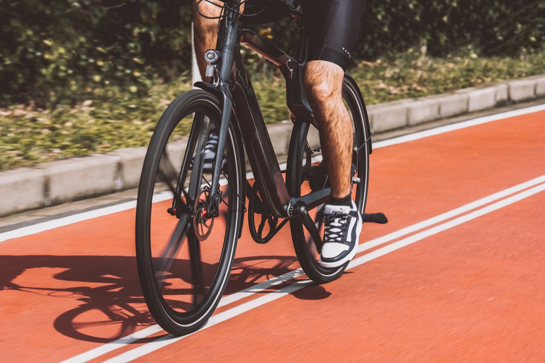 Close-up of a cyclist pedaling on a road bike with a power meter visible.