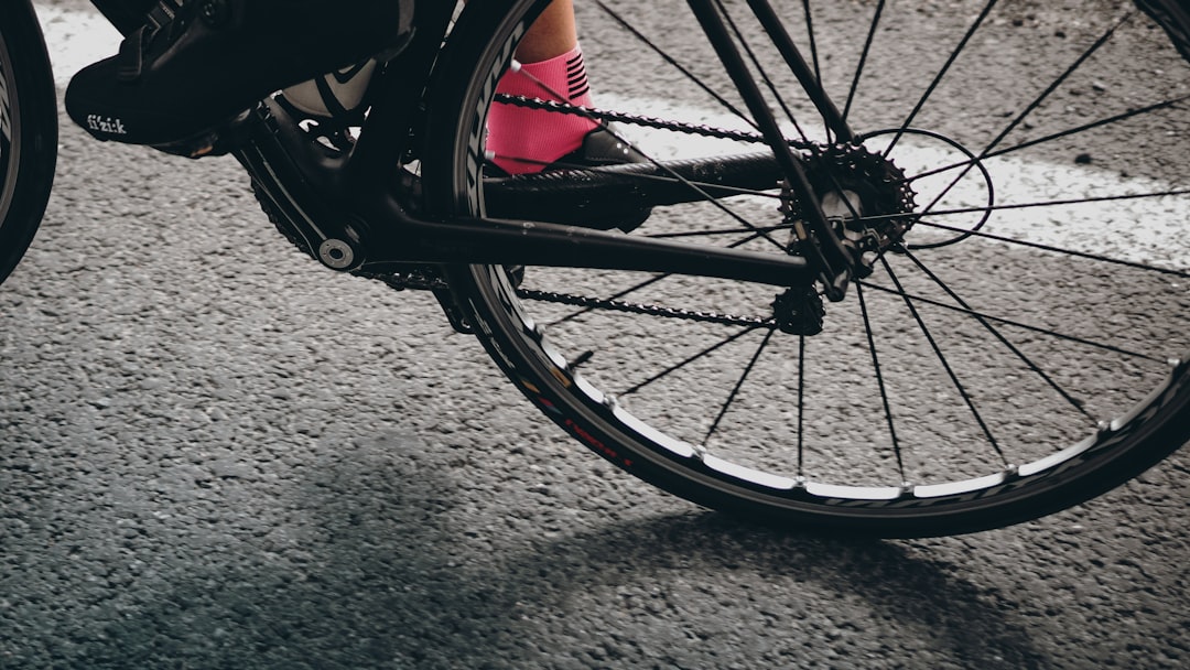 Close-up of a cyclist pedaling on a road bike with a power meter visible.