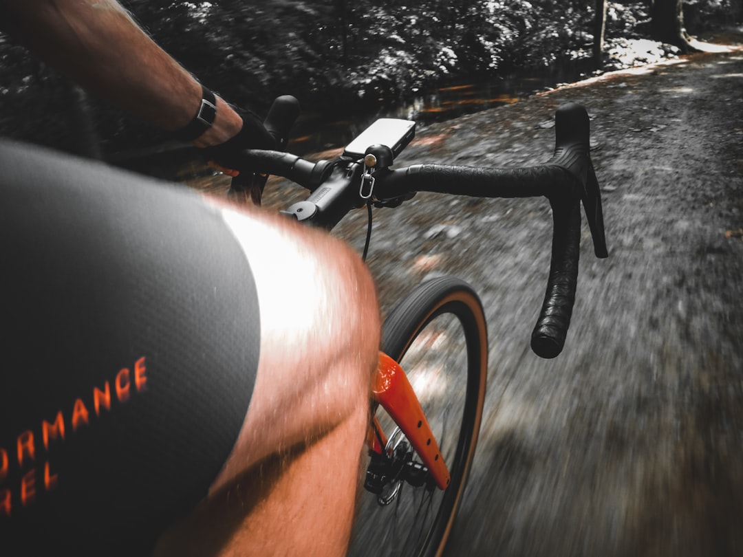 Close-up of a cyclist pedaling on a road bike with a power meter visible.