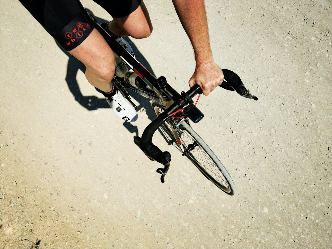 Close-up of a cyclist pedaling on a road bike with a power meter visible.