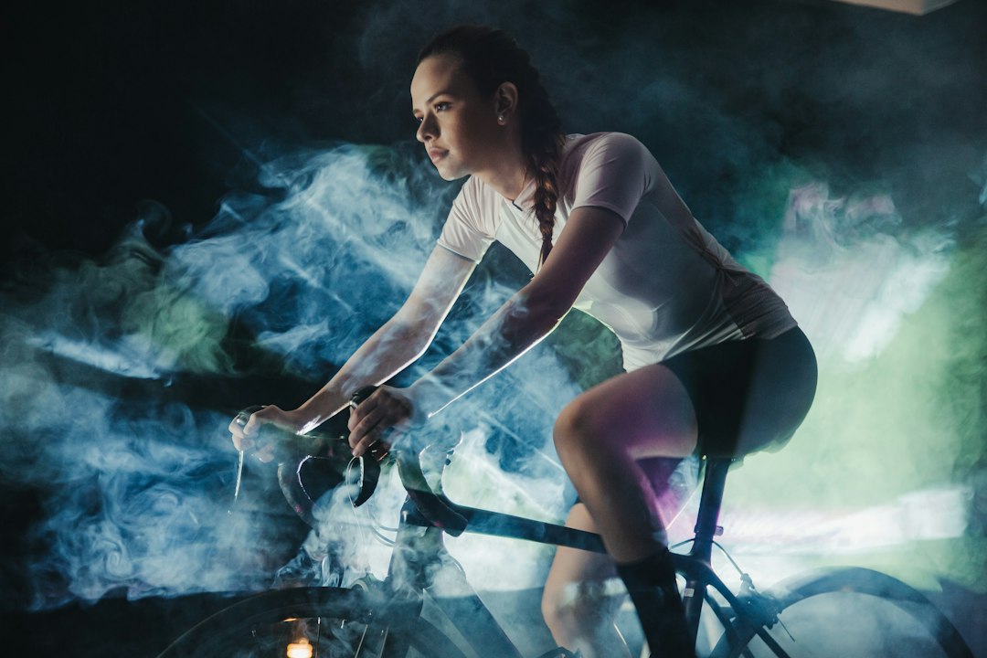 Close-up of a cyclist pedaling on a road bike with a power meter visible.