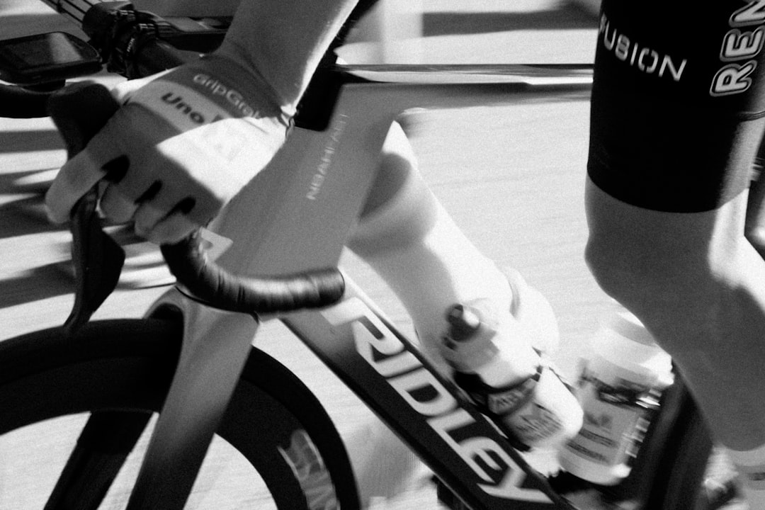 Close-up of a cyclist pedaling on a road bike with a power meter visible.