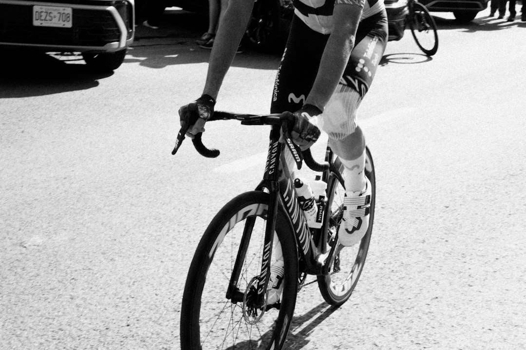 Close-up of a cyclist pedaling on a road bike with a power meter visible.