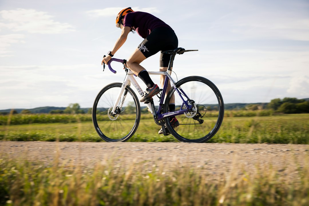 Close-up of a cyclist pedaling on a road bike with a power meter visible.